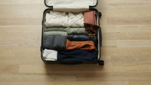 An open suitcase filled with a neatly organized 3 week travel capsule wardrobe.