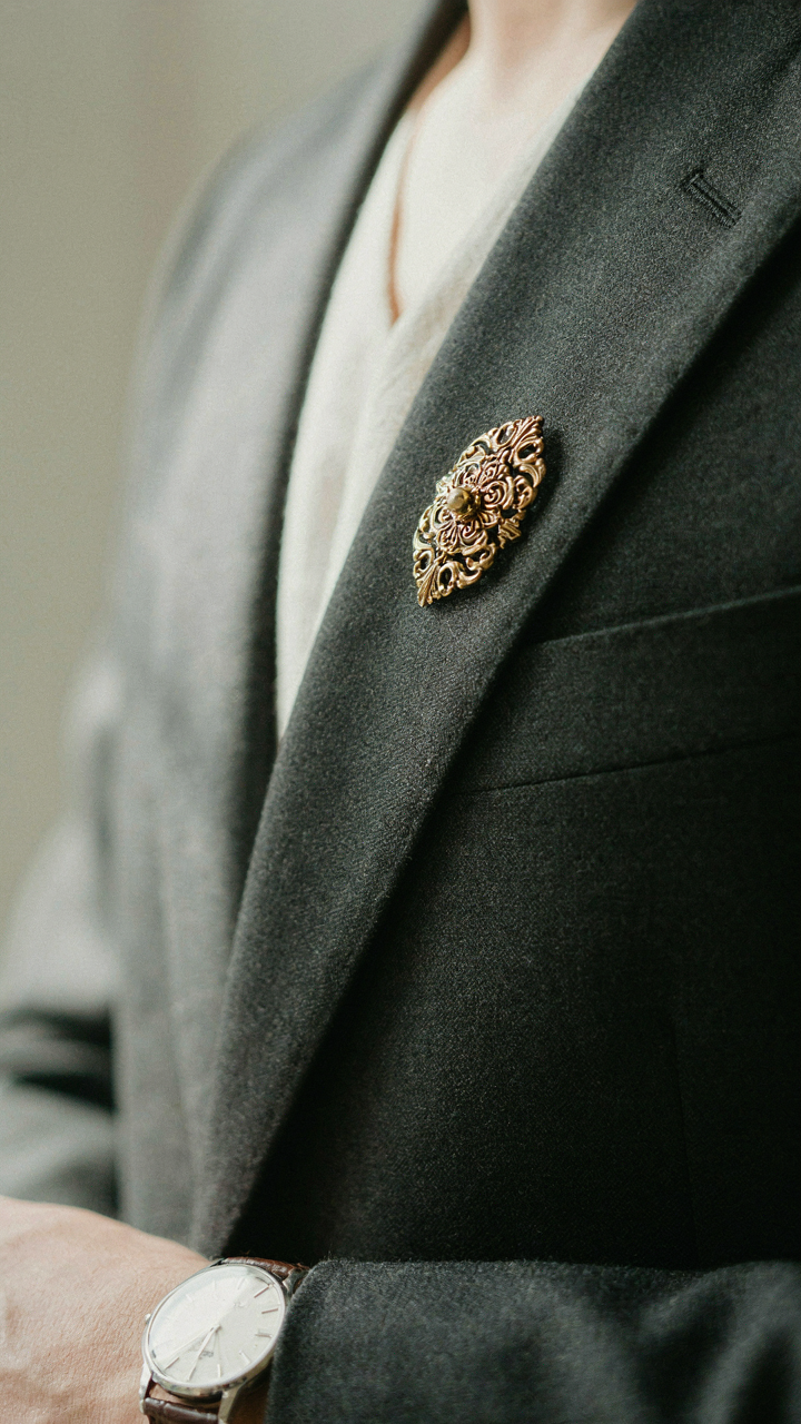 An elegant vintage brooch on a blazer lapel with a watch.
