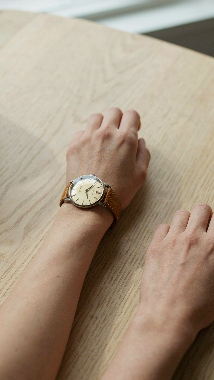 A close-up of a vintage leather watch on a woman's wrist.