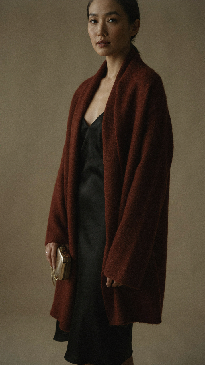 Woman holding a small metallic clutch, wearing a cashmere wrap over a dress.
