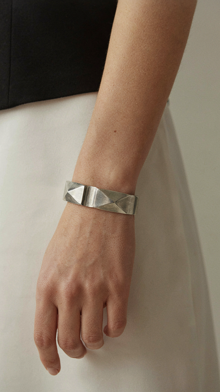 A woman wearing a geometric silver cuff bracelet on a black dress.