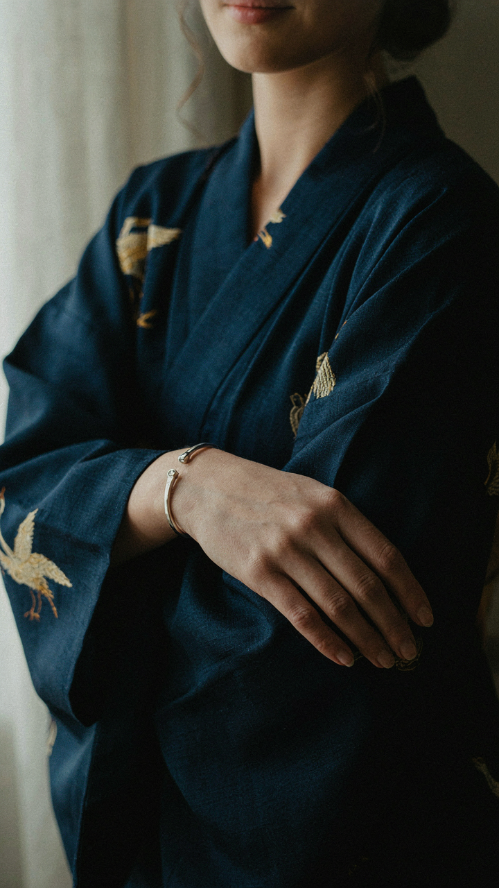 A woman's hand wearing a silver bracelet on a kimono jacket sleeve.