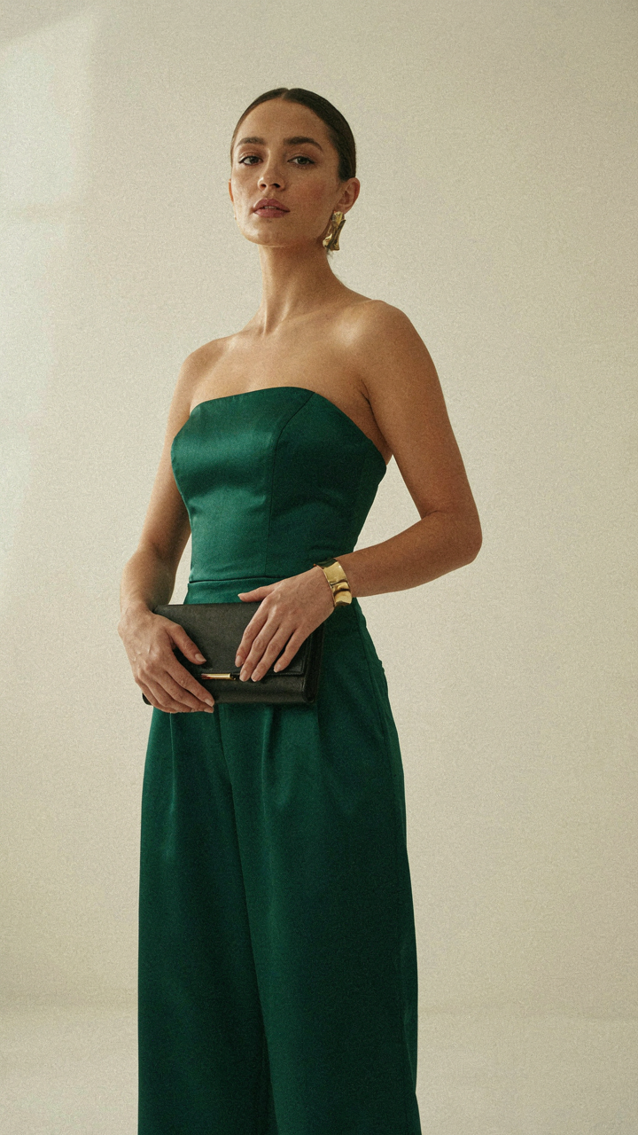 A woman in a strapless jumpsuit wearing a bold cuff bracelet and earrings.