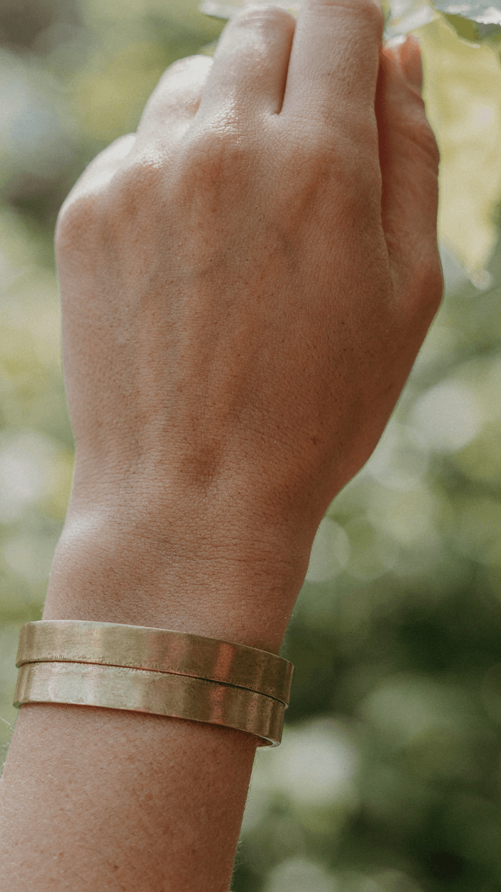 A woman's hand shows a substantial bracelet catching sunlight.