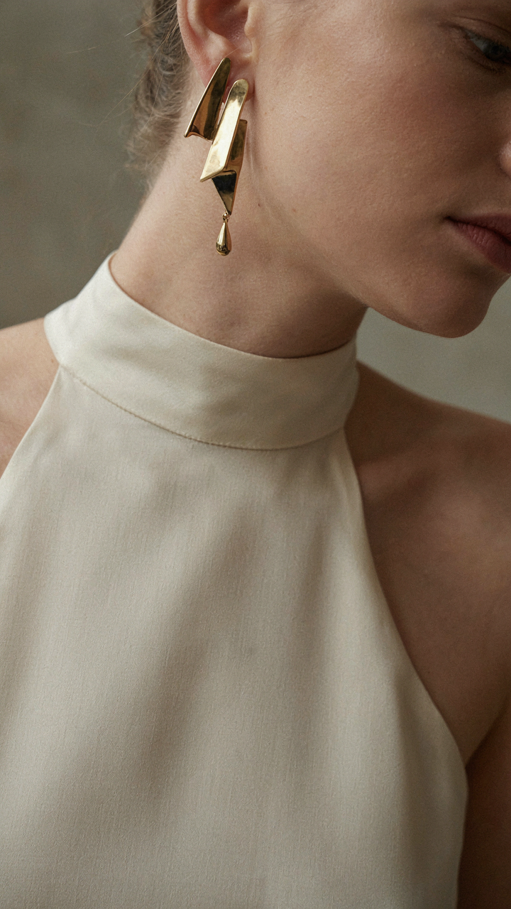 A single architectural earring stands out against a dress's high neckline.