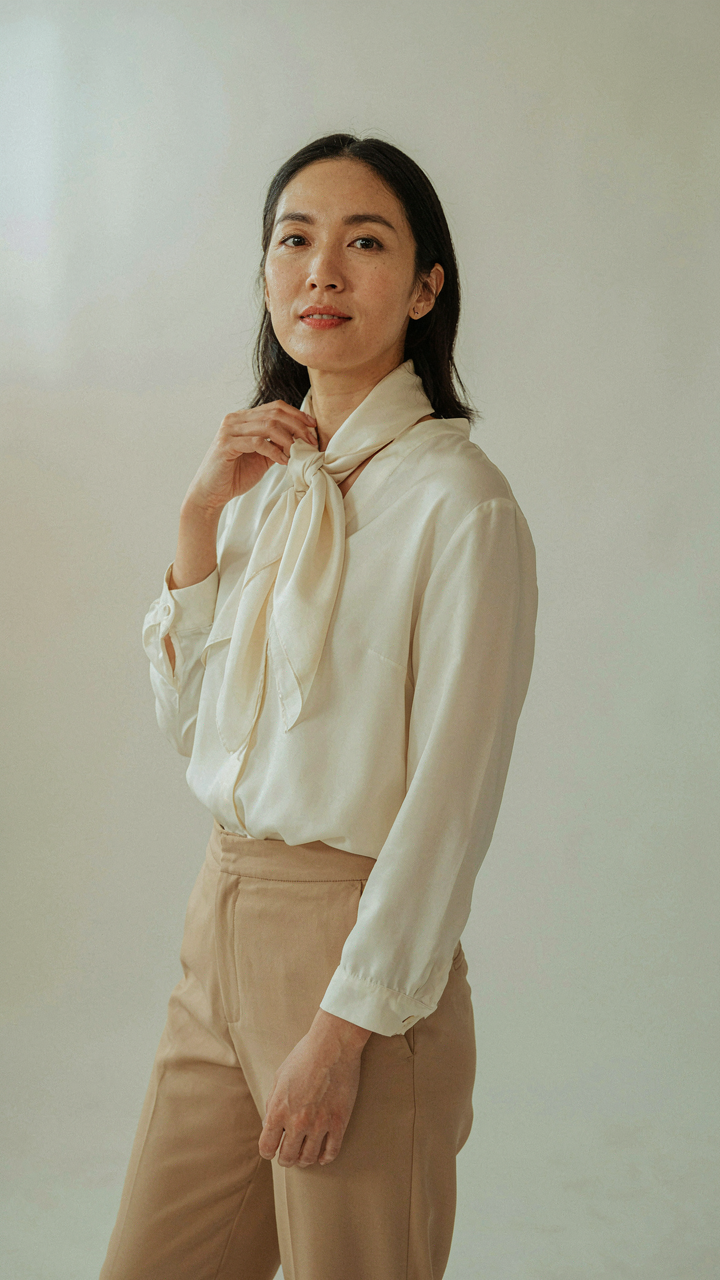 A woman wears a silk scarf, catching the light and enhancing her outfit.