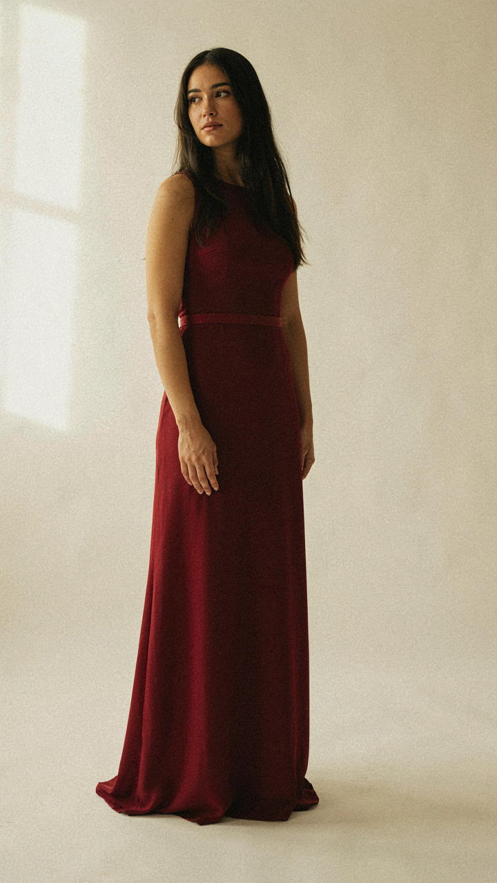 A woman wears a burgundy maxi dress with belt placed high, creating length.