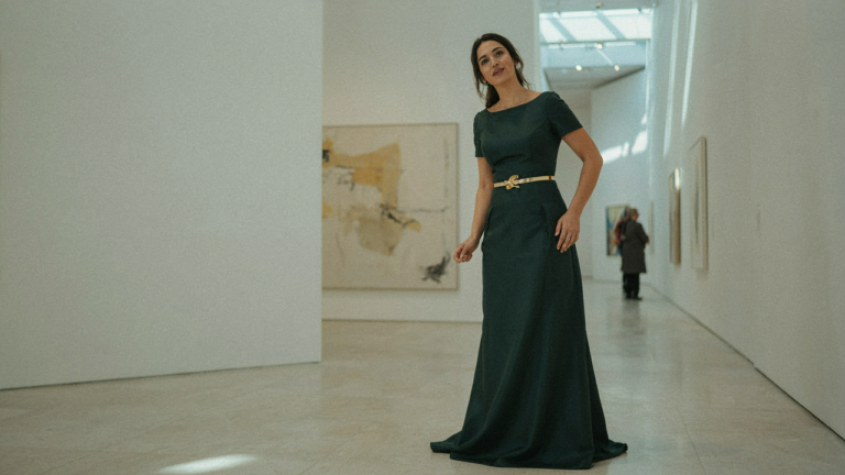 A woman wears an emerald formal dress with belt, accentuating her waist.