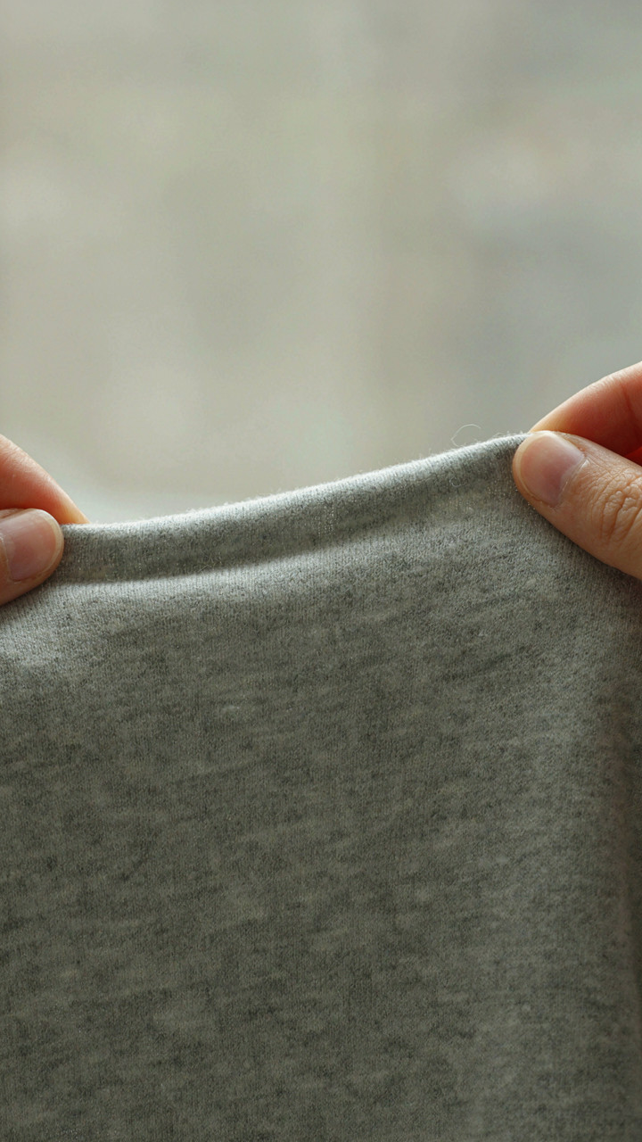 A close up of light gray merino wool fabric showing its natural elasticity.