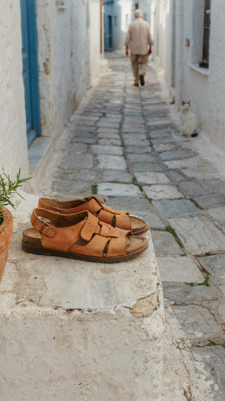 Leather sandals with arch support on a worn cobblestone street.