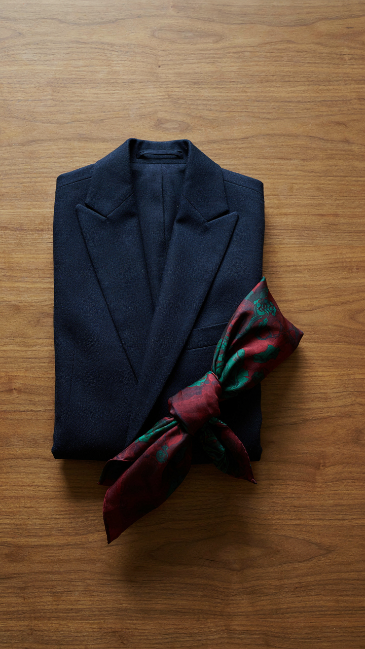 A navy blazer and a contrasting textured fabric swatch lie on a wooden table.
