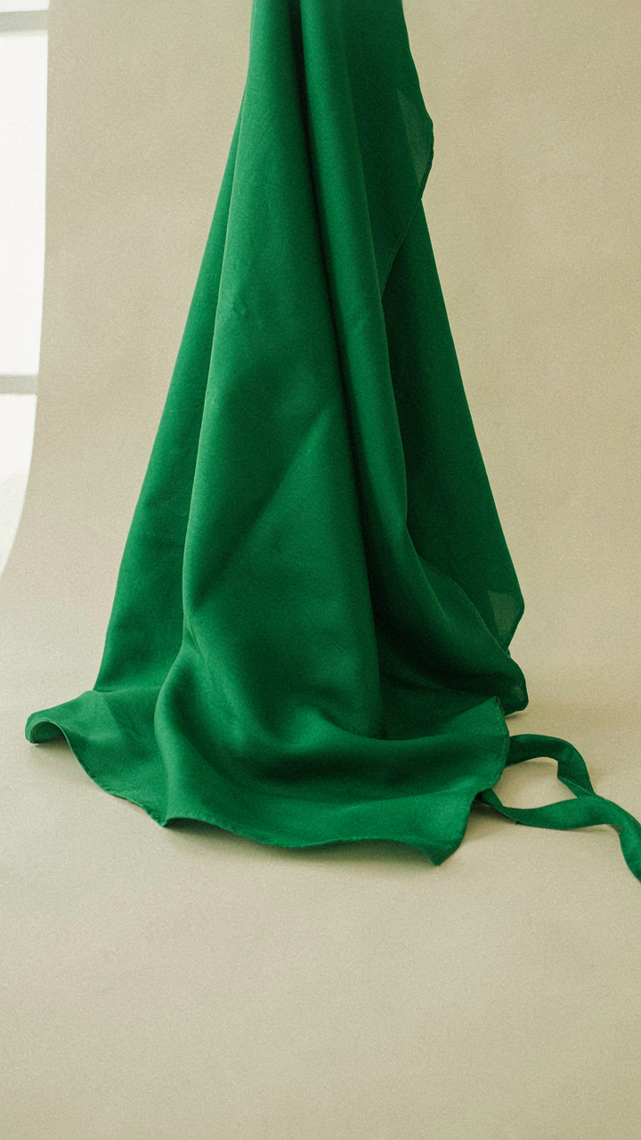 Emerald green silk fabric draped elegantly, highlighting its rich color.