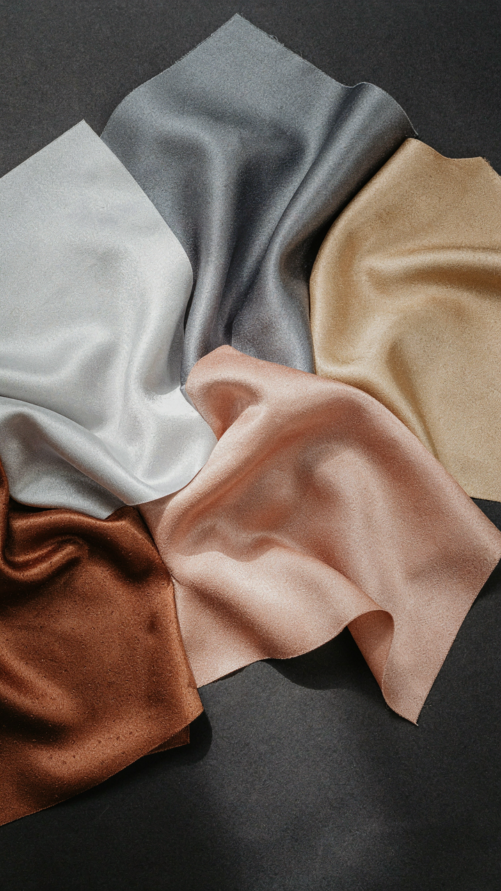A collection of smooth and textured metallic fabric swatches reflects light.