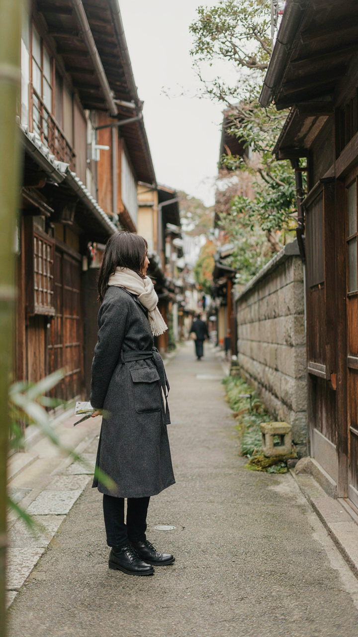 A person in charcoal and cream blends into a quiet Kyoto alley.