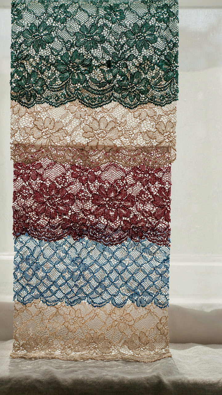 Lace swatches in jewel tones and nudes held against natural light.