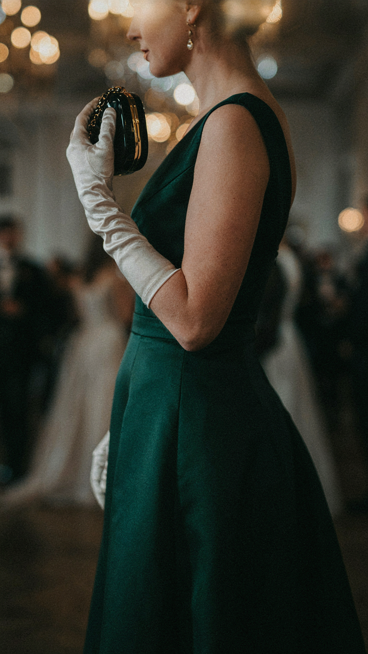 A gloved hand holding a clutch bag at a formal evening gala.