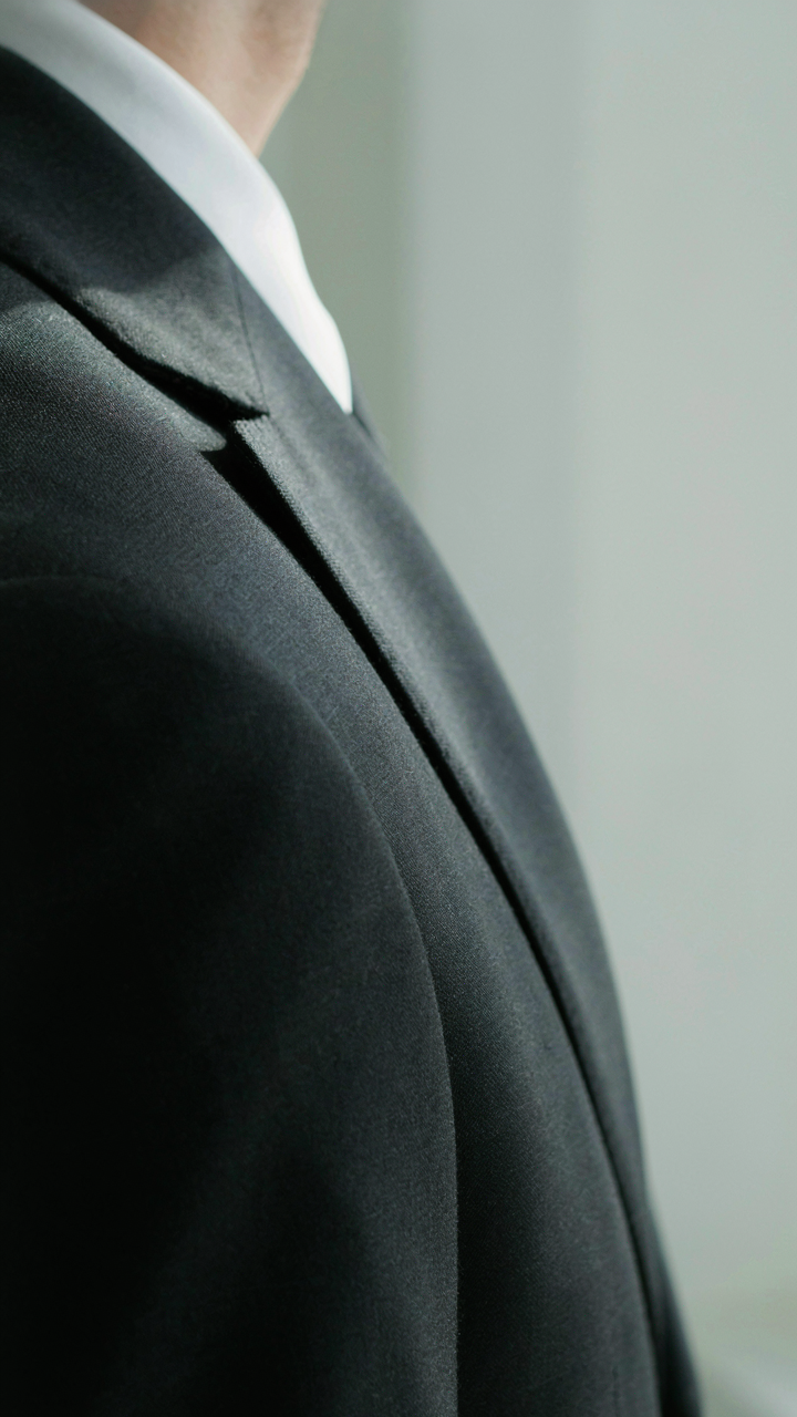 A close-up of a well-tailored dark suit jacket shoulder.