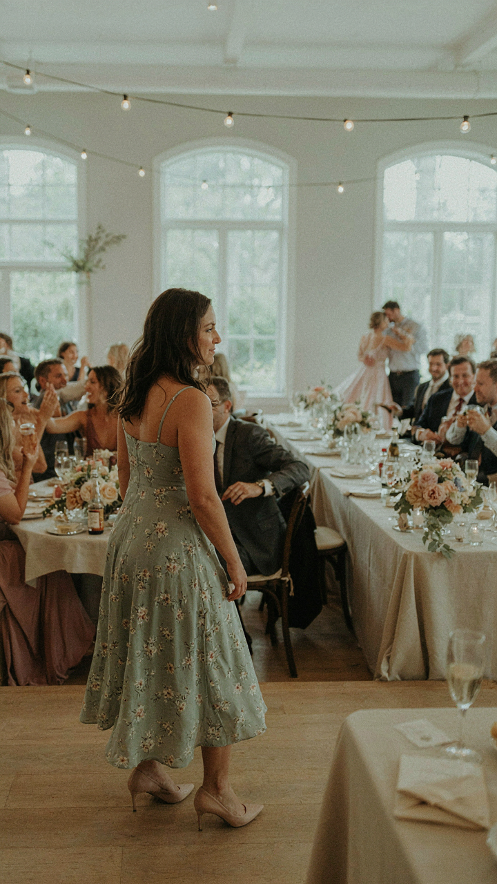 Woman in a midi dress observing a lively wedding reception.