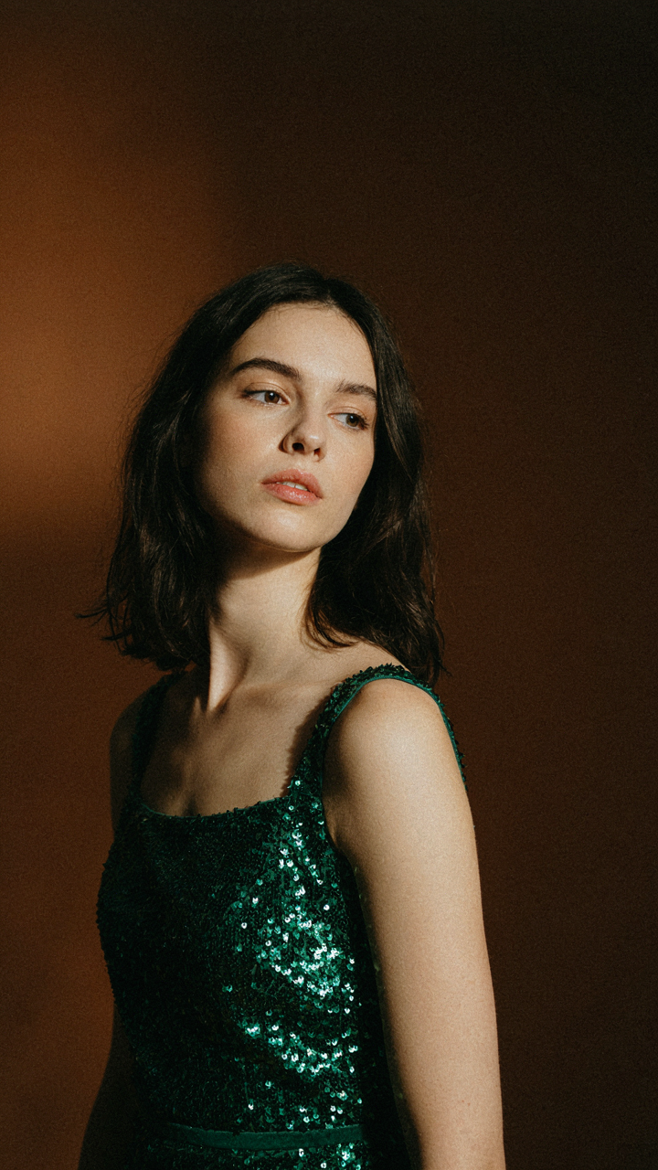 An emerald green sequin top stands out vividly against a dark background.