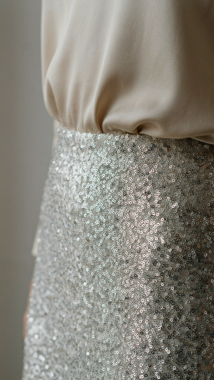 A close-up of a sequin skirt paired with a smooth, matte cream top.