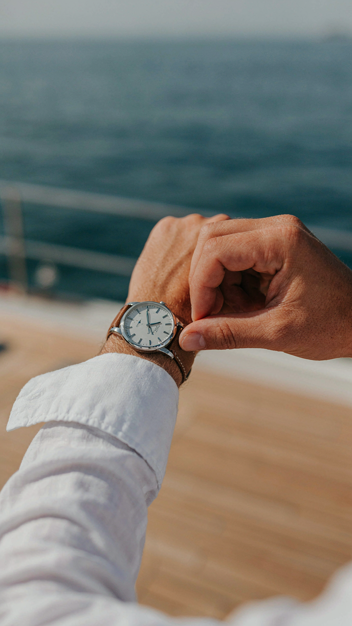 Hand subtly adjusts a quality watch on a yacht, emphasizing understated elegance.