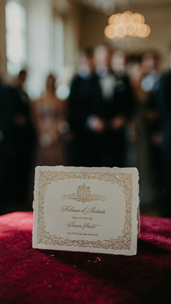 A formal event invitation on velvet, with a blurred crowd in the back.