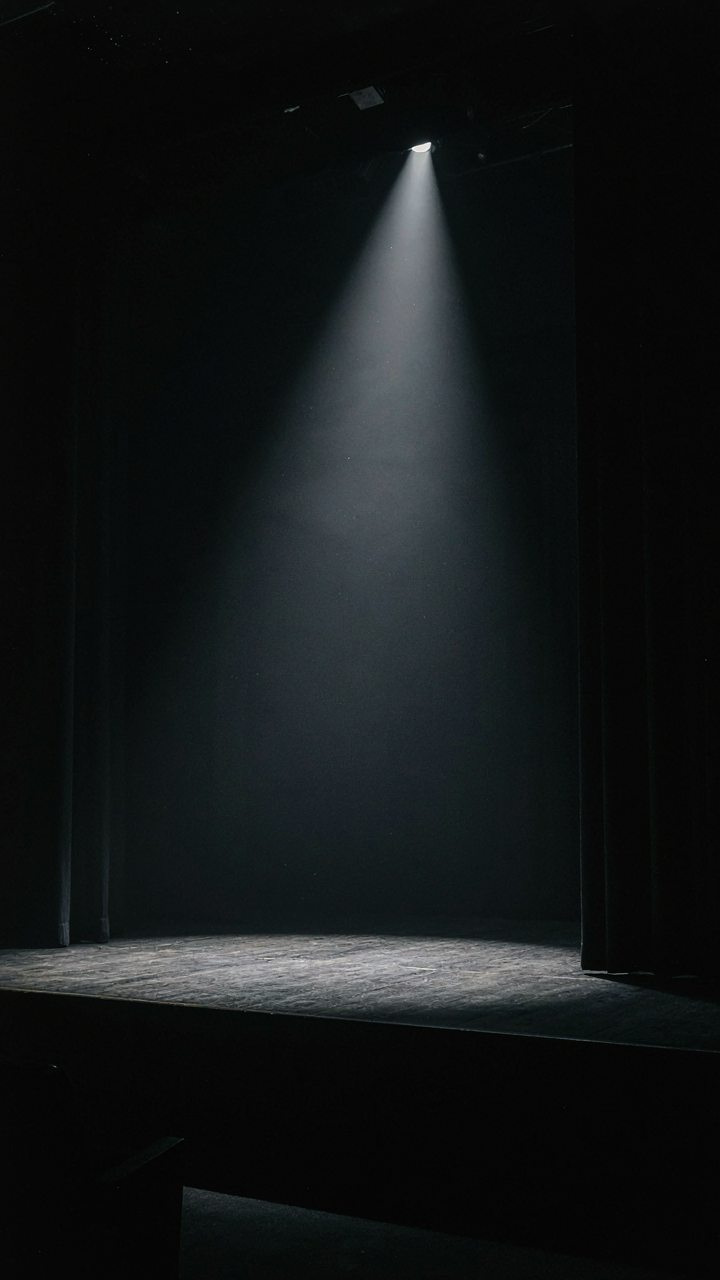 A bright spotlight focuses on a small stage.