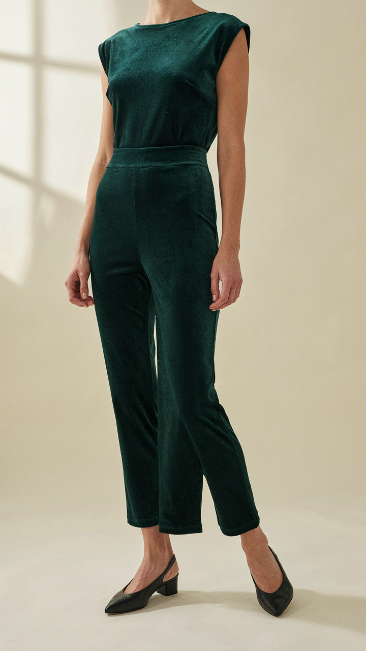 A woman wears a perfectly tailored velvet jumpsuit with pointed flat shoes.