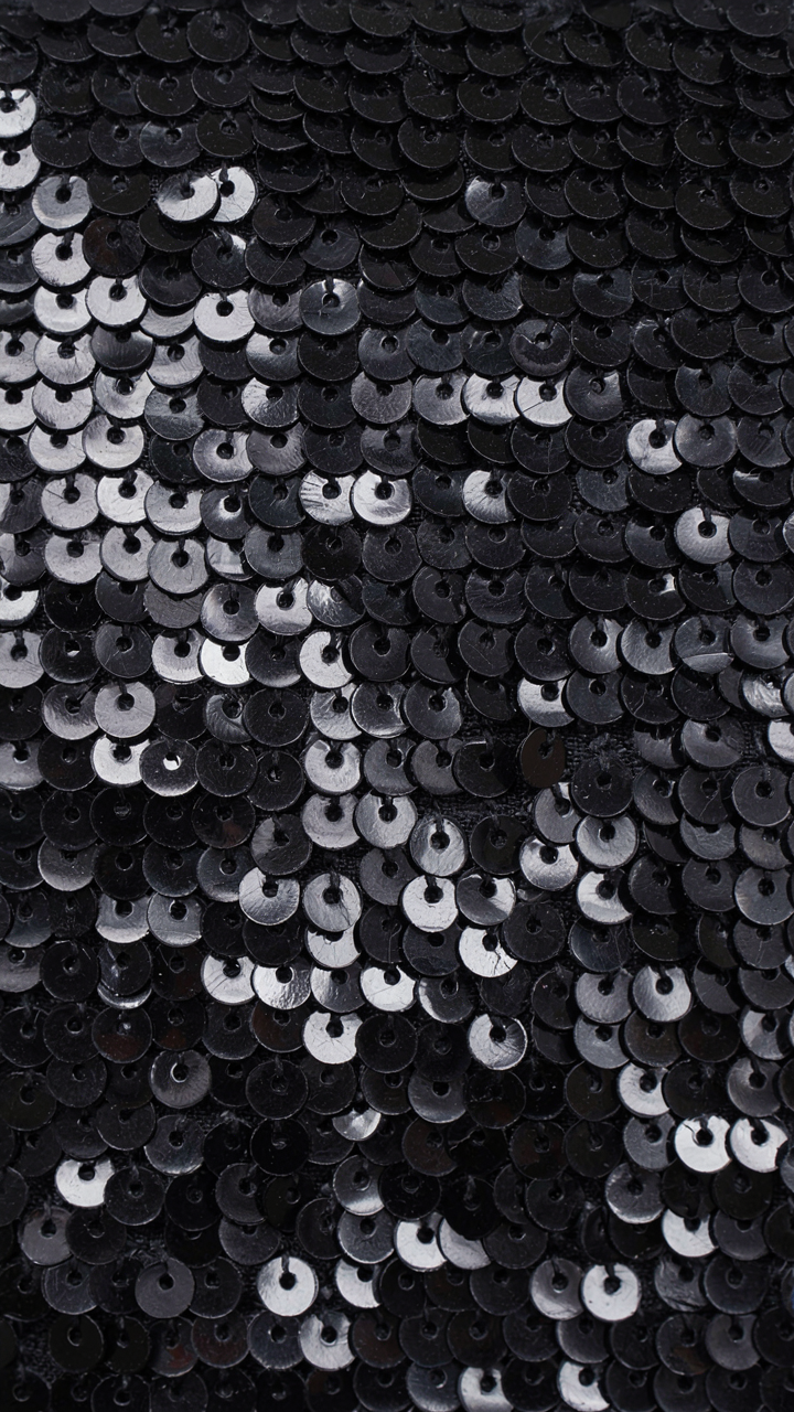 Close-up of densely placed, tonal black sequins on a structured fabric.