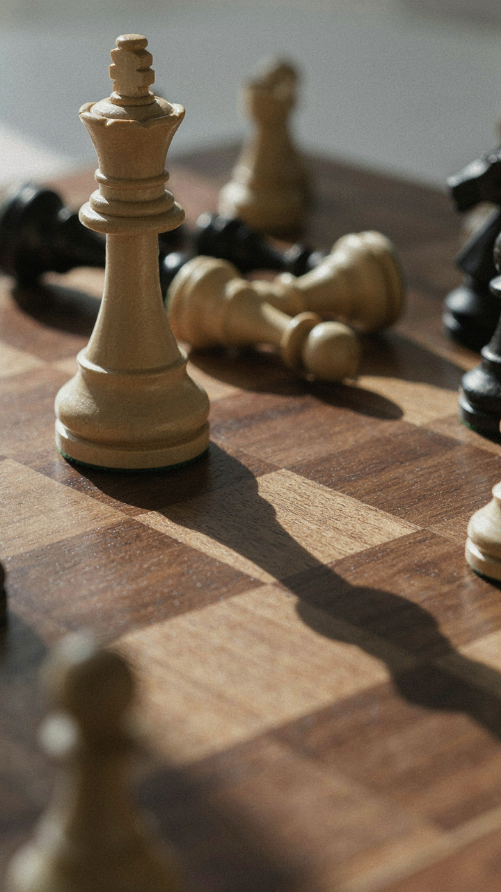 A chess queen casting a long shadow over other pieces on a chessboard.