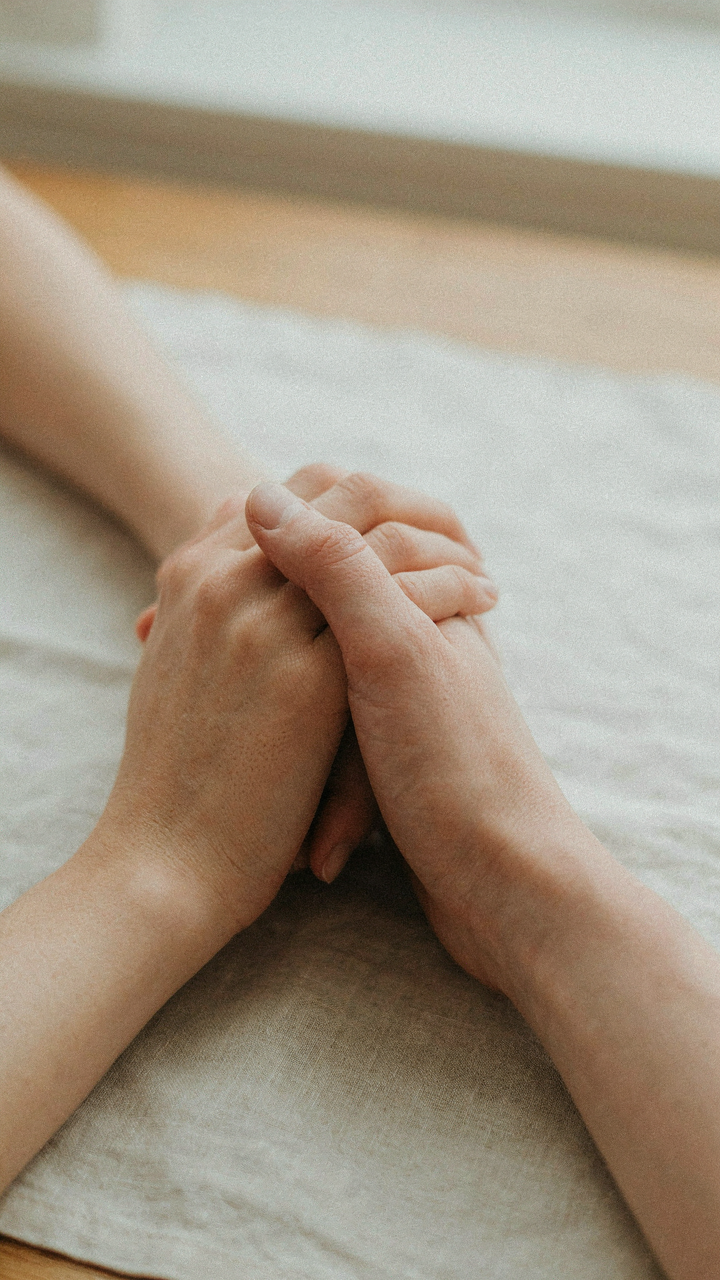 Close-up of two people's gently intertwined hands.