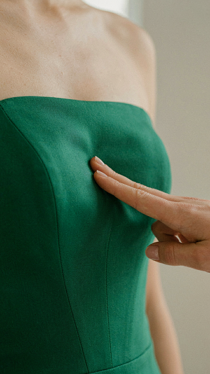 A hand presses a finger into the structured bodice of a strapless jumpsuit.