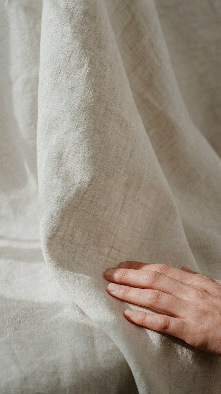 A hand gently touches a high-quality cotton-linen blend fabric.
