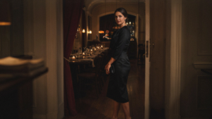 An elegant woman in a black birthday dinner cocktail dress enters a restaurant.