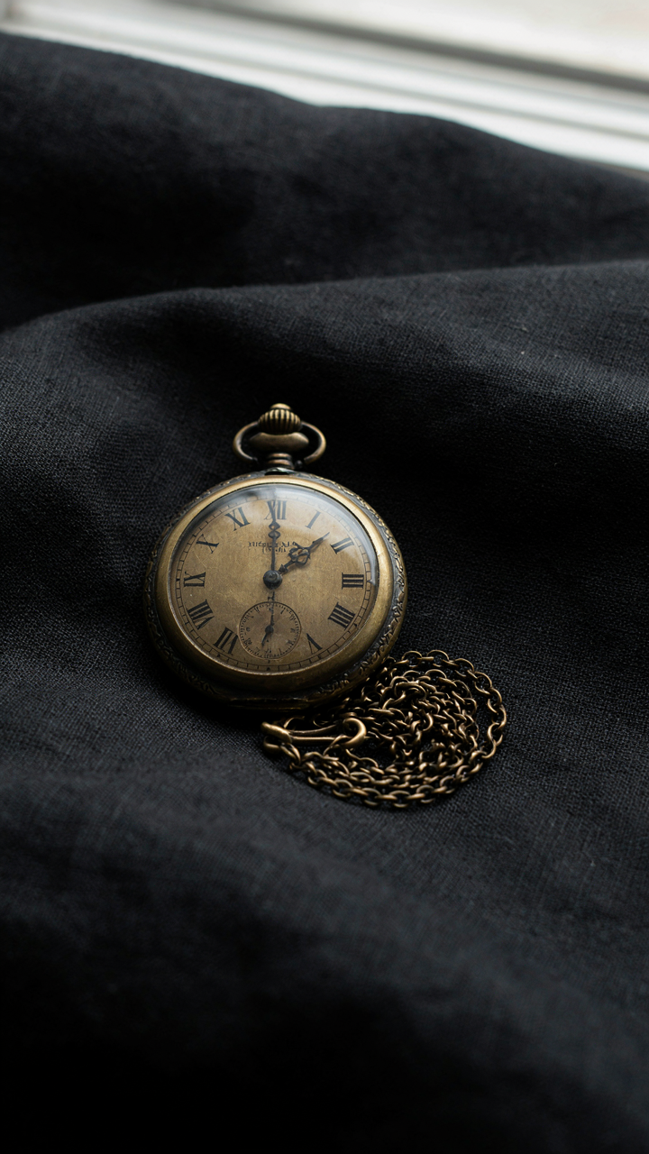 An old, well-worn vintage pocket watch on a black fabric.