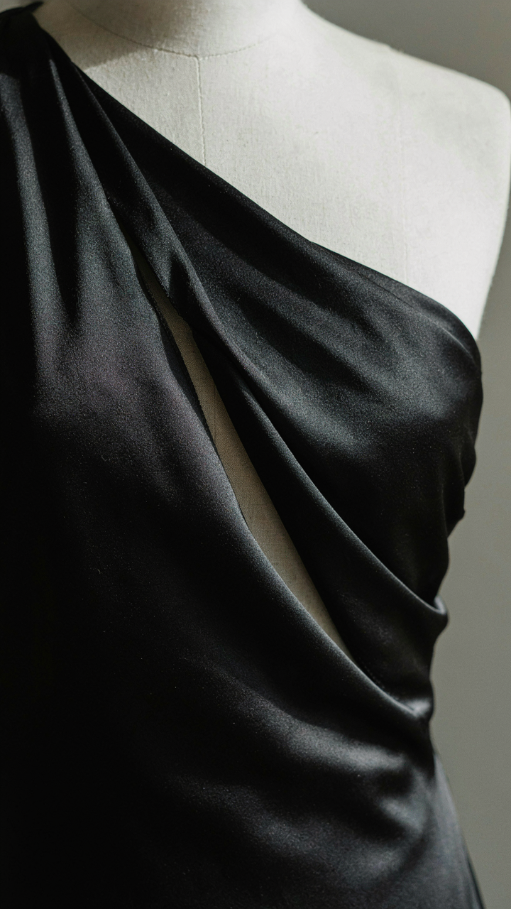 Close-up of a black silk charmeuse dress with an asymmetrical neckline.