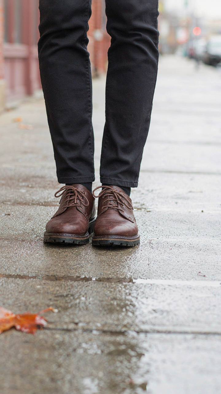 A person's feet in sturdy, closed-toe shoes with good grip on a wet pavement.