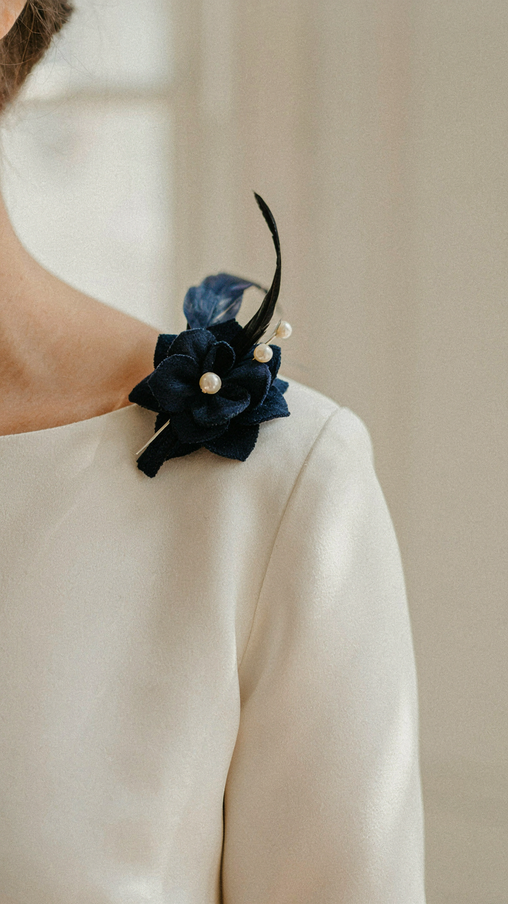 A stylish navy blue fascinator placed on an ivory silk dress.