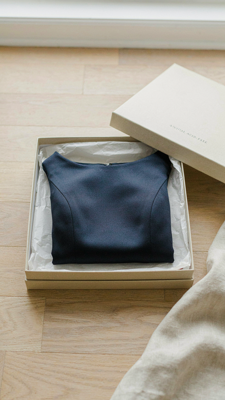 Navy boat neck cocktail dress neatly folded in an archival storage box.