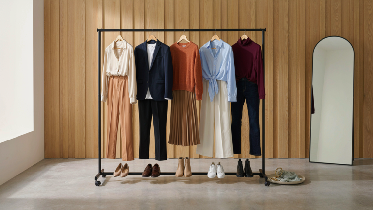 Five complete business casual outfits hanging neatly in a bright dressing room.
