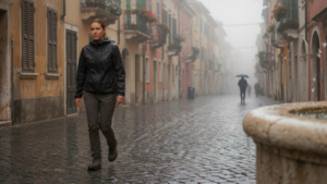 A person walks on a rainy street, wearing a capsule wardrobe for rainy destinations.