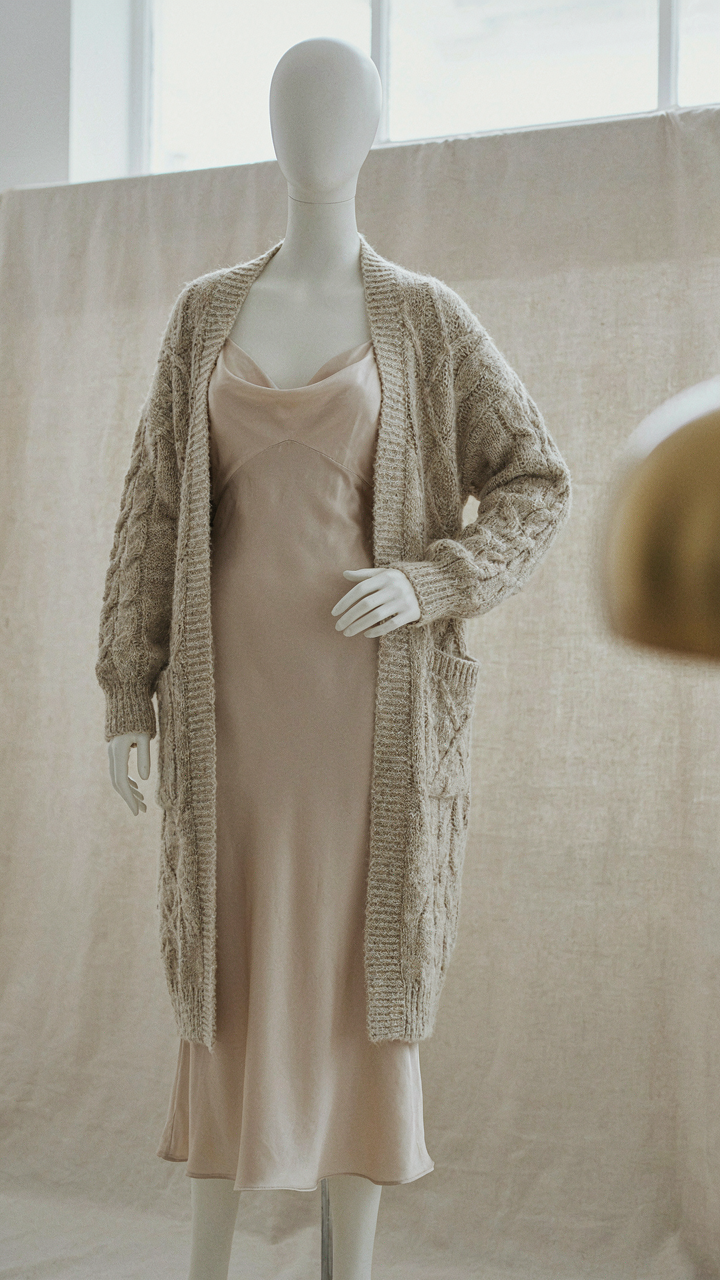 Silk slip dress visible under a structured, long knit cardigan.