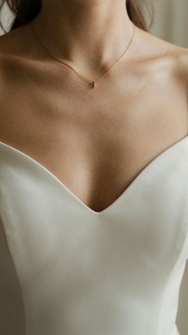 A woman's collarbones framed by a sweetheart neckline on a bodycon dress.