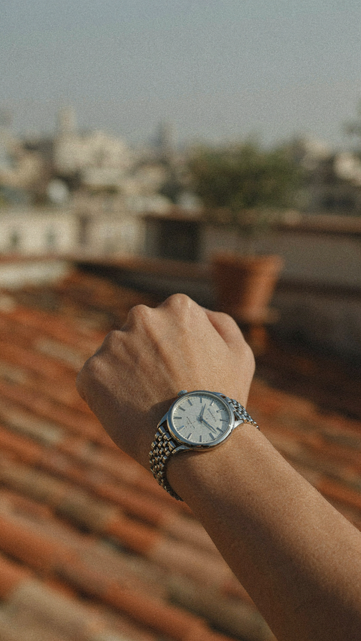 A person's wrist wears a classic, elegant wristwatch as a focal point accessory.