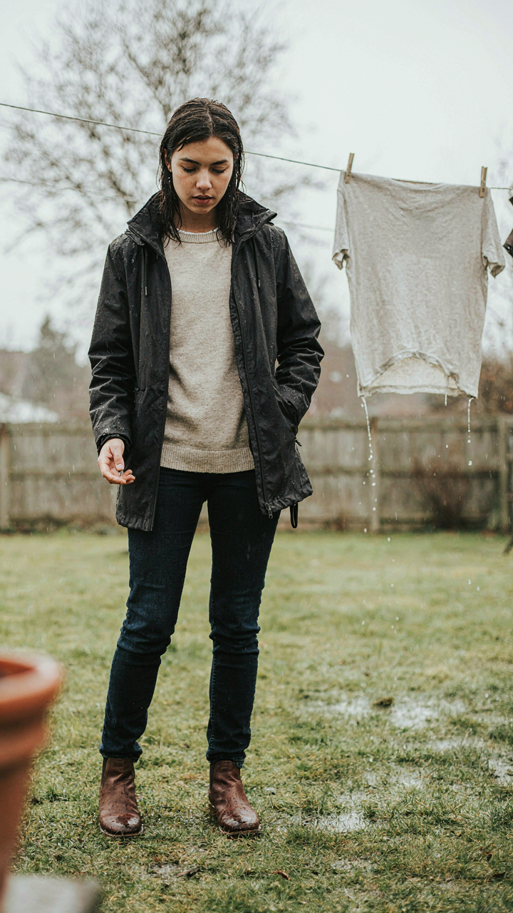 Person in a synthetic jacket and merino sweater, a wet cotton shirt hangs nearby.