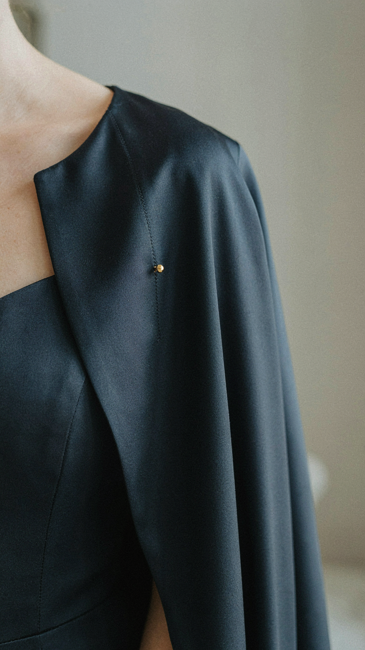 A close-up of a secure hook-and-eye closure on an evening cape.