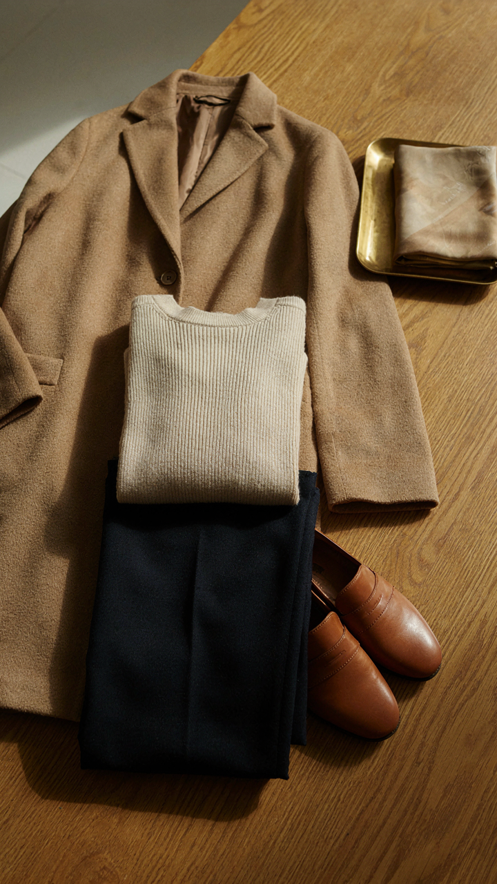 A collection of clothes in neutral colors like navy, cream, and camel.