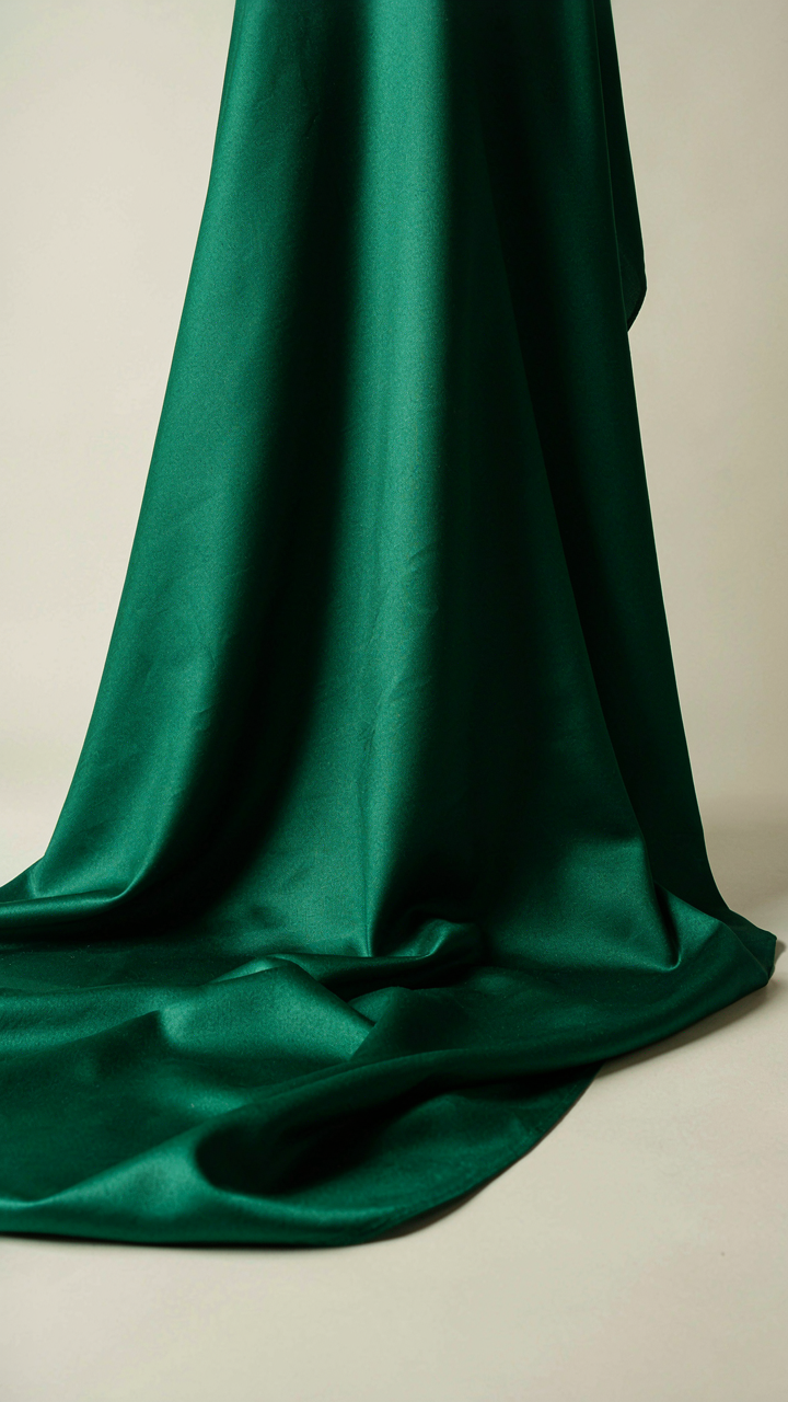 Rich emerald green silk fabric draped elegantly, showing deep shadows.