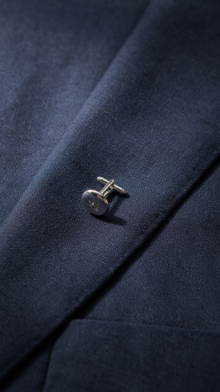 A close-up of midnight blue formal fabric with a silver cufflink.