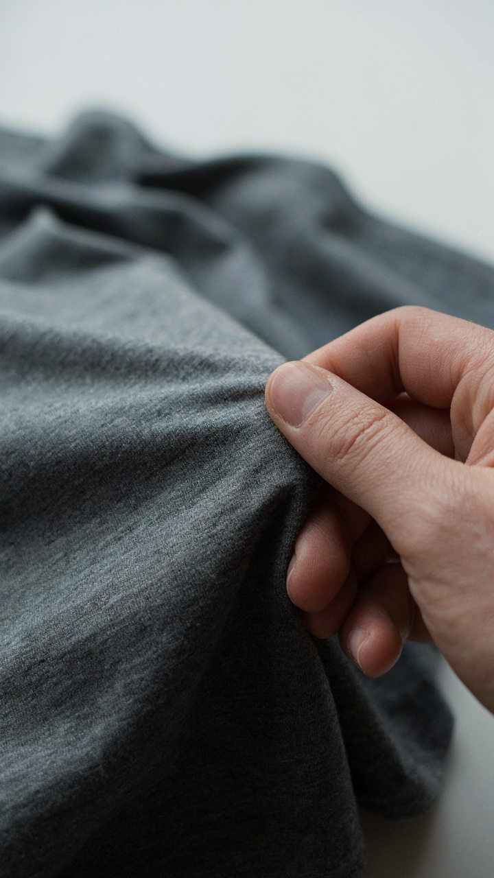 A hand stretches comfortable, elastic fabric for casual cocktail attire.